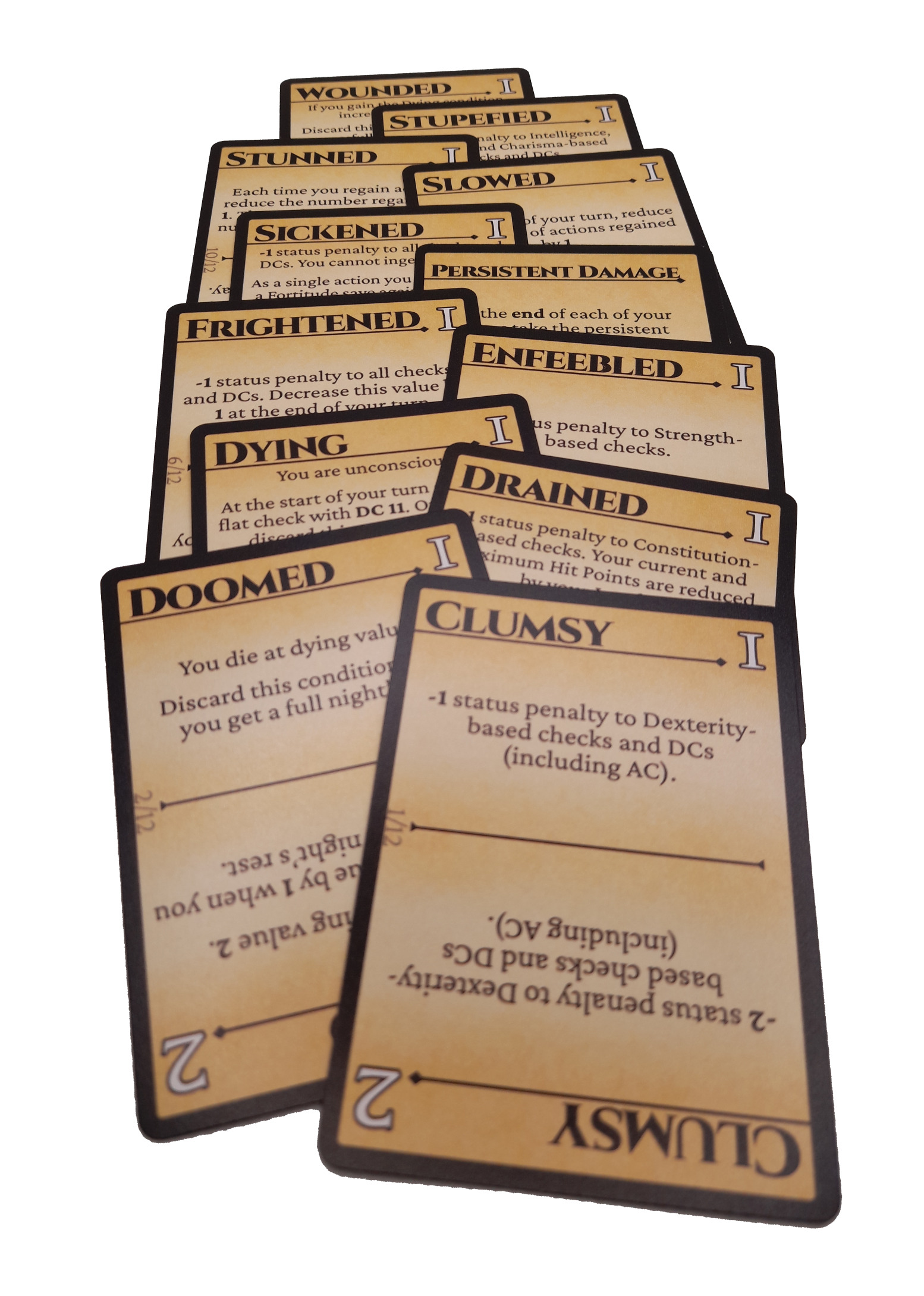 CONDITIONS! cards stack on top of each other. Each card has a bold title and black outline and can be rotated to have different numbers on the top right corner. The cards are labeled: Clumsy, Doomed, Drained, Dying, Enfeebled, Frightened, Persistent Damage, Sickened, Slowed, Stunned, Stupefied, and Wounded.